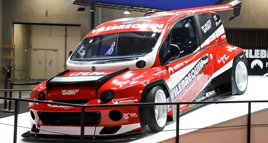 Vilebrequin Fiat 1000Tipla with Rocket Bunny widebody kit at Le Mans circuit, front three-quarter view showing rear wing and red livery
