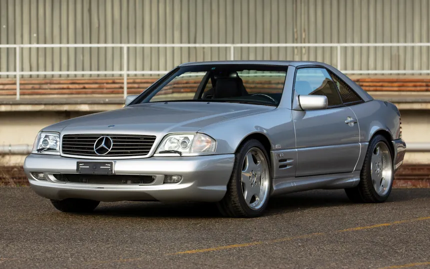 Mercedes-Benz SL 500 R129 convertible in brilliant silver on a Mediterranean coastal road at golden hour