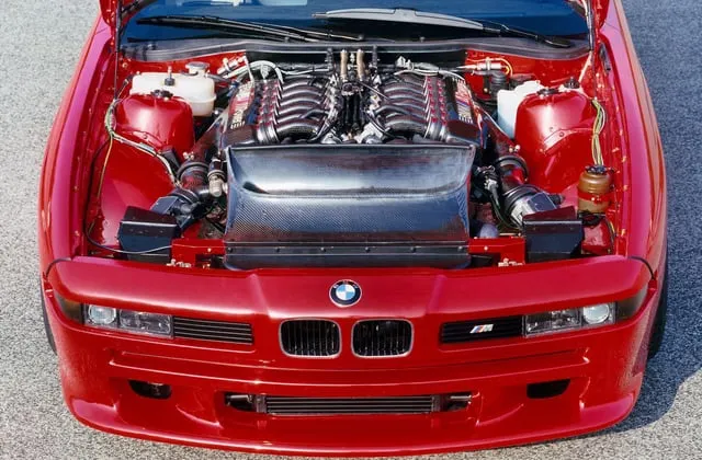 BMW M8 E31 prototipo en rojo brillante visto desde tres cuartos delantero mostrando faros integrados en paragolpes capó sin retráctiles y carrocería aligerada