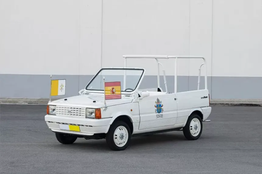 Papamóvil blanco con cúpula de cristal blindado elevada sobre plataforma, rodeado de multitud, iluminación dramática ceremonial