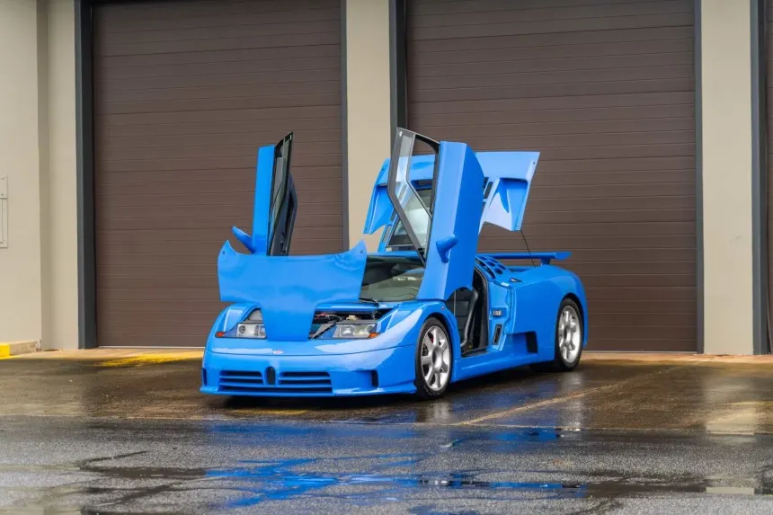 Blue Bugatti EB110 GT with open scissor doors at the Campogalliano factory