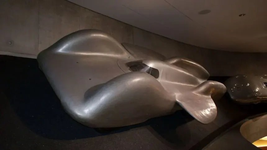 Bare chassis of the Mercedes-Benz T80 land speed record car displayed engine-less at the Mercedes-Benz Museum in Stuttgart, showing the three-axle six-wheeled Ferdinand Porsche design